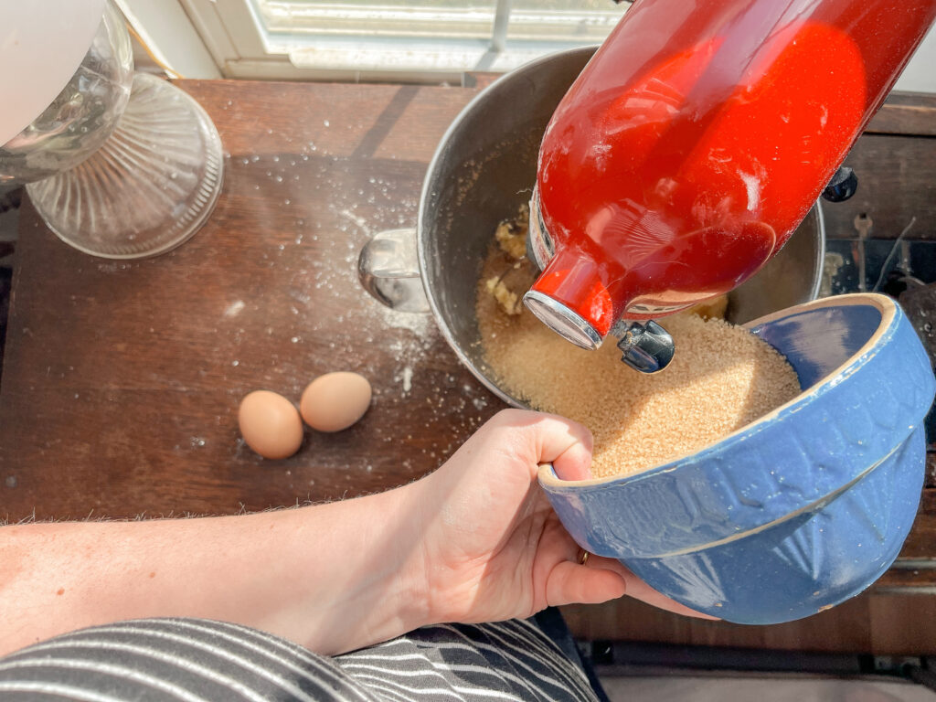 red kitten aid mixer mixing sugar and butter with eggs sitting next. apple sauce einkorn cake