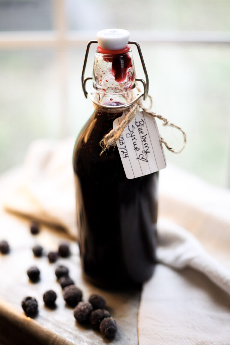 a bottle of blueberry syrup with frozen blueberries