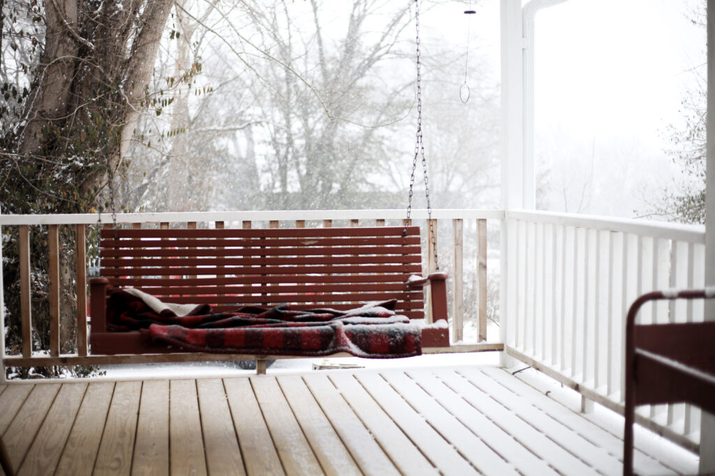 red porch swing covered in snow in the winter time