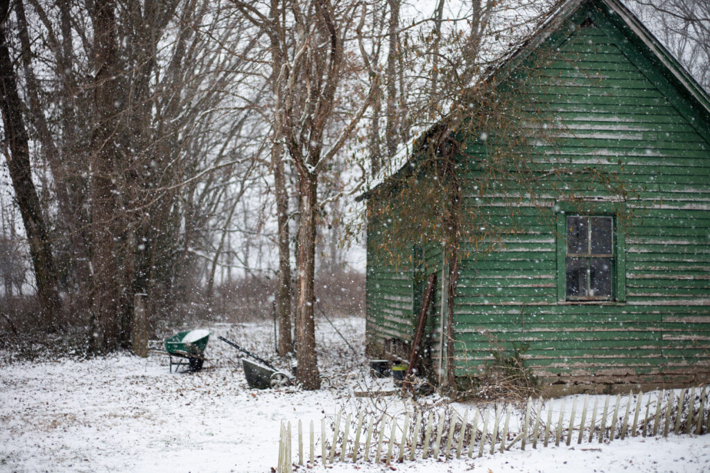 snow falling on an old farm